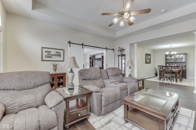 living room featuring a tray ceiling, a barn door, and light wood-type flooring