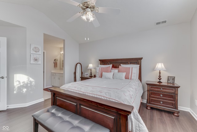 bedroom with ceiling fan, dark hardwood / wood-style floors, vaulted ceiling, and ensuite bath