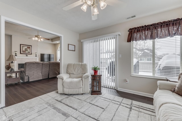 living room with a tile fireplace and ceiling fan