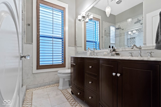 bathroom featuring vanity, an inviting chandelier, toilet, a wealth of natural light, and a tile shower