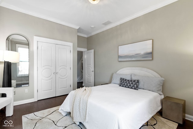 bedroom with dark hardwood / wood-style floors, ornamental molding, and a closet