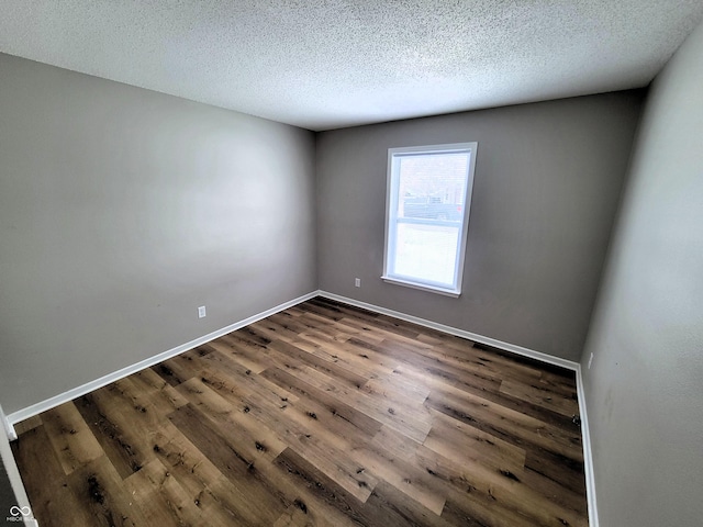 spare room featuring dark wood-type flooring and a textured ceiling