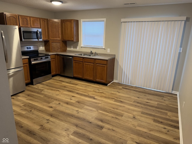 kitchen with sink, light hardwood / wood-style floors, a textured ceiling, and appliances with stainless steel finishes