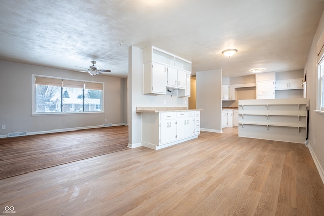 kitchen with white cabinets, light wood-type flooring, and ceiling fan