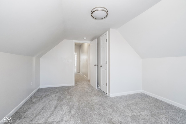 additional living space with light colored carpet and vaulted ceiling