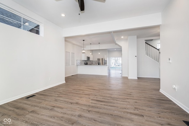 unfurnished living room featuring hardwood / wood-style flooring and ceiling fan