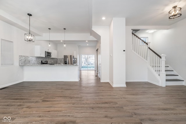 kitchen with pendant lighting, white cabinets, tasteful backsplash, kitchen peninsula, and stainless steel appliances