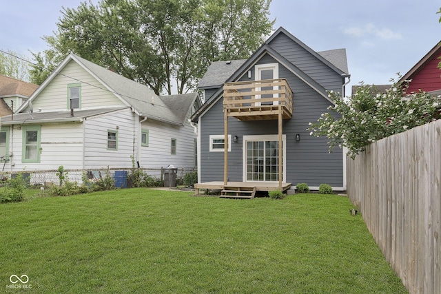 rear view of property featuring a yard, a balcony, and a wooden deck