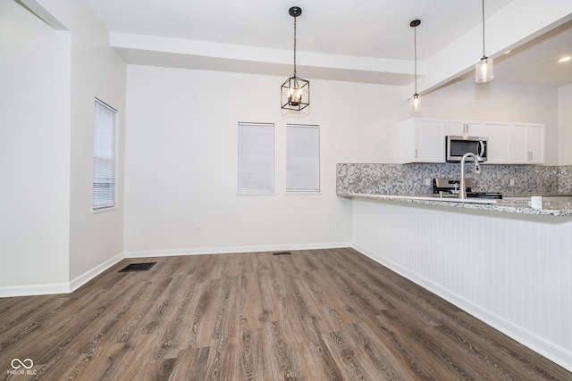 kitchen with white cabinets, hanging light fixtures, decorative backsplash, appliances with stainless steel finishes, and light stone counters