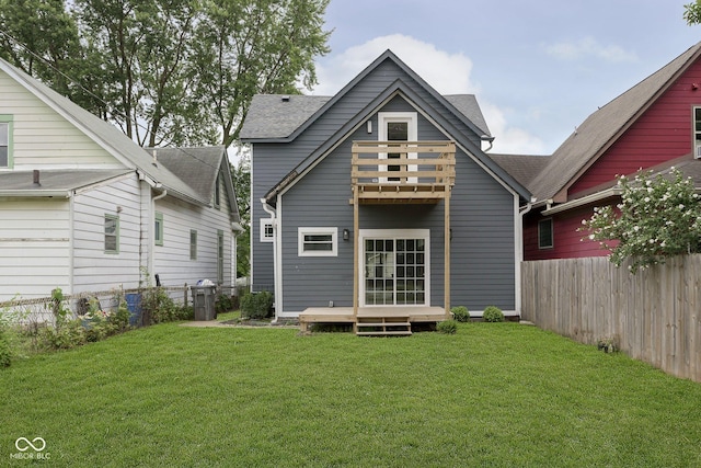 rear view of property with a yard, a balcony, and a deck