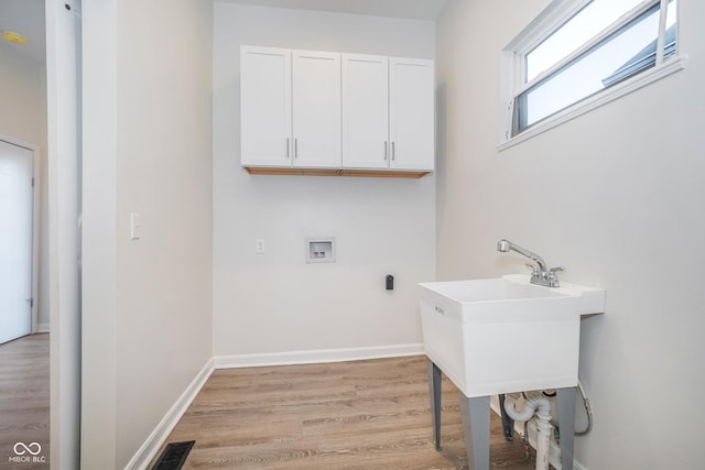 laundry room featuring washer hookup, light hardwood / wood-style floors, cabinets, and sink