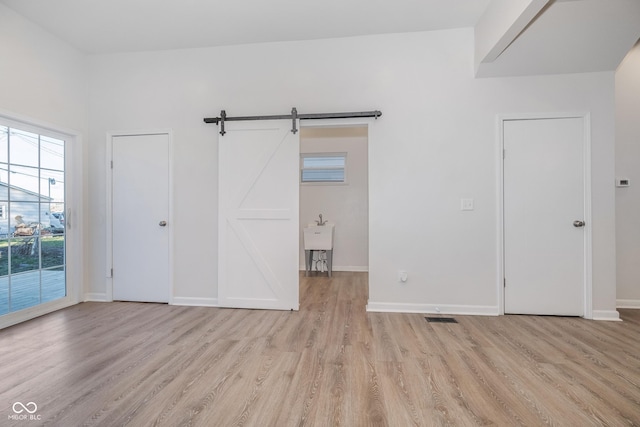 empty room with a barn door and light wood-type flooring