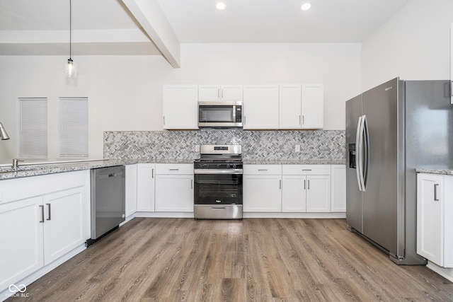 kitchen featuring backsplash, white cabinetry, hanging light fixtures, and appliances with stainless steel finishes