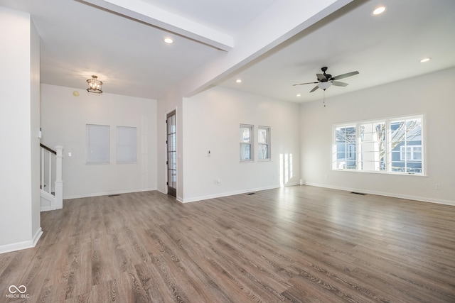 unfurnished living room featuring beamed ceiling, wood-type flooring, and ceiling fan