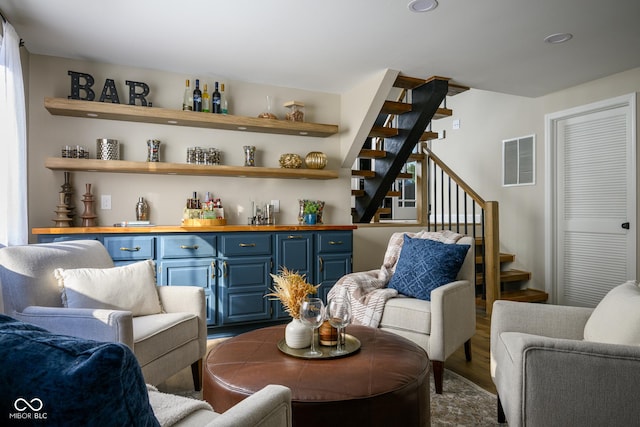 living area with bar and wood-type flooring