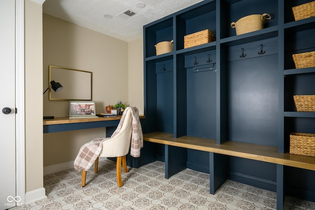 mudroom with a textured ceiling and built in desk