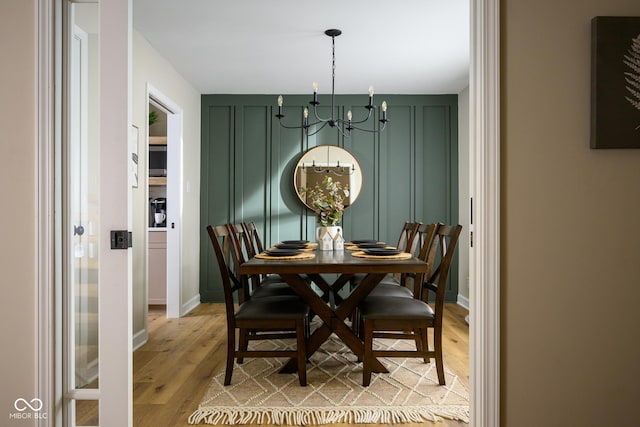 dining space with light hardwood / wood-style flooring and a chandelier