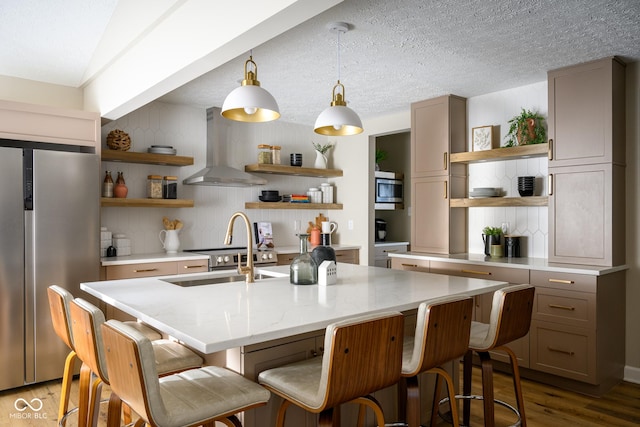 kitchen with extractor fan, stainless steel appliances, a center island with sink, decorative backsplash, and sink