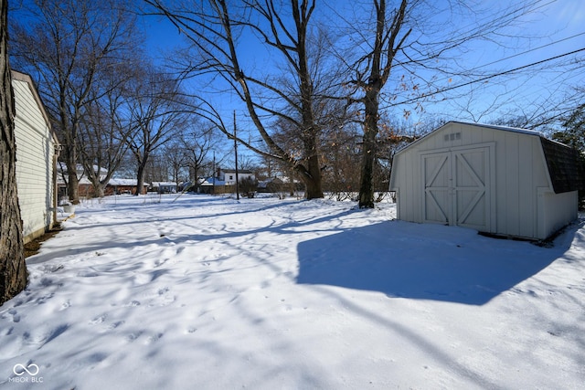 snowy yard featuring a storage unit