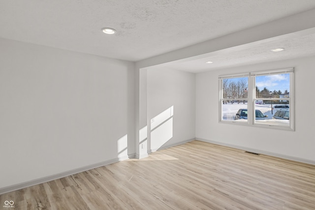 empty room featuring light wood-type flooring and a textured ceiling