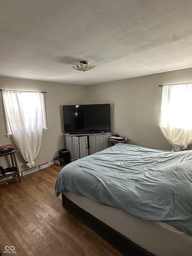 bedroom featuring hardwood / wood-style flooring and a baseboard heating unit