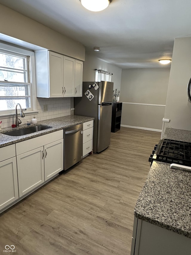 kitchen with decorative backsplash, stainless steel appliances, white cabinetry, and sink