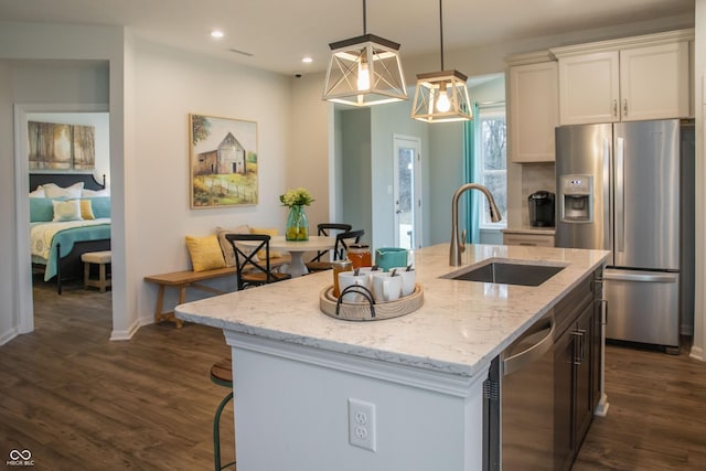 kitchen featuring a center island with sink, white cabinets, sink, decorative light fixtures, and stainless steel appliances