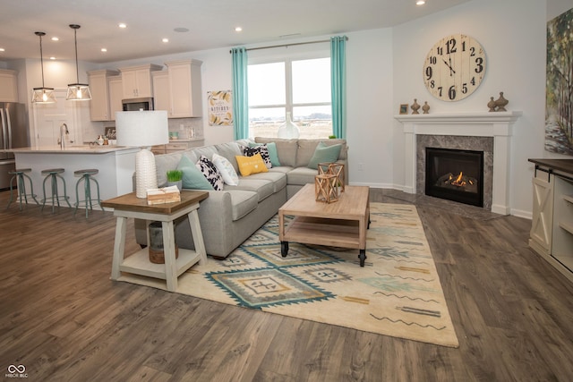 living room featuring a fireplace, sink, and dark wood-type flooring