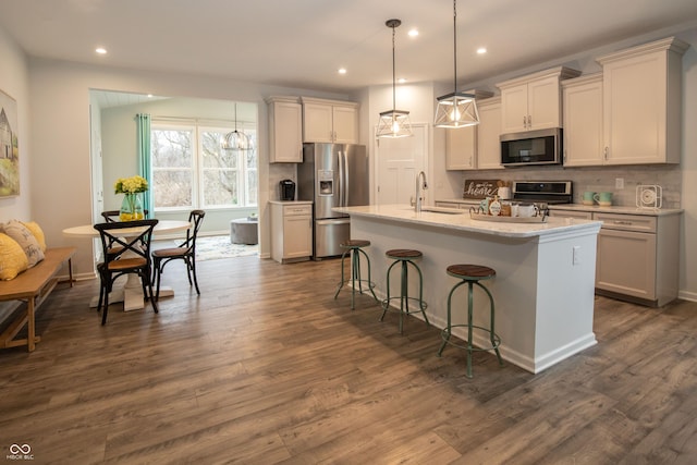 kitchen featuring hanging light fixtures, sink, appliances with stainless steel finishes, and an island with sink