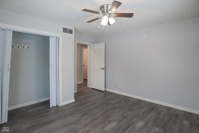 unfurnished bedroom with ceiling fan, dark wood-type flooring, a textured ceiling, and a closet