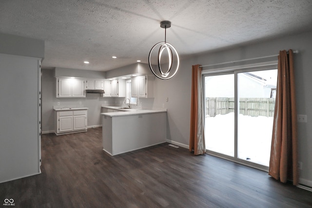 kitchen featuring decorative light fixtures, dark wood-type flooring, white cabinets, and kitchen peninsula