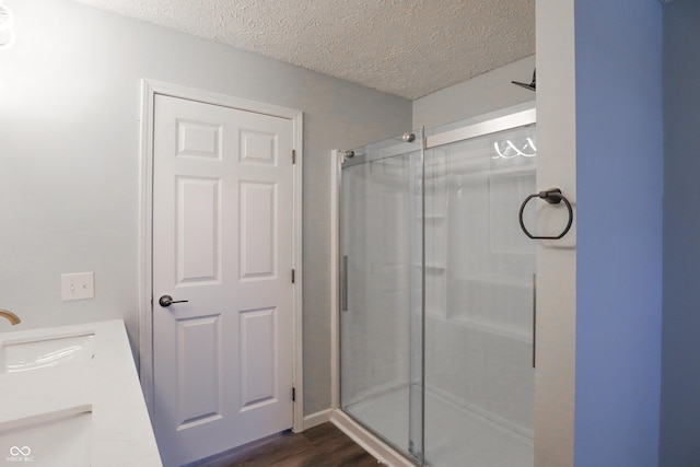 bathroom with vanity, hardwood / wood-style floors, a textured ceiling, and a shower with shower door