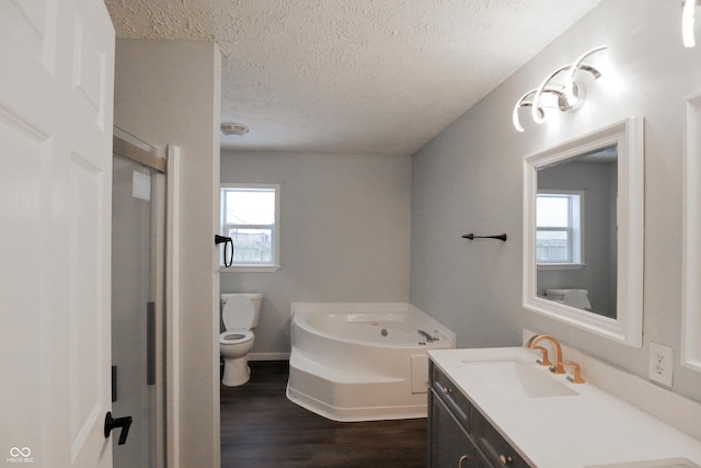 bathroom with a bathing tub, hardwood / wood-style floors, vanity, toilet, and a textured ceiling