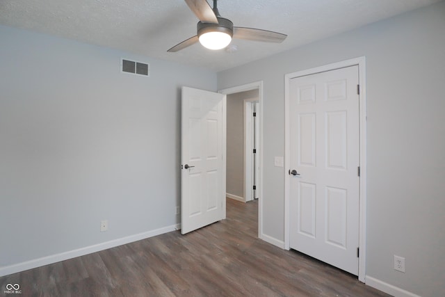 unfurnished bedroom with ceiling fan, dark hardwood / wood-style floors, and a textured ceiling