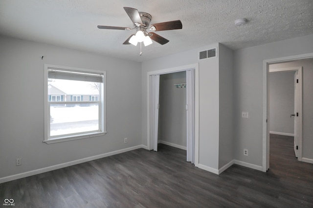 unfurnished bedroom with ceiling fan, dark hardwood / wood-style floors, a textured ceiling, and a closet