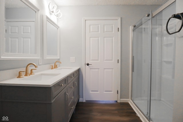 bathroom with hardwood / wood-style flooring, vanity, an enclosed shower, and a textured ceiling