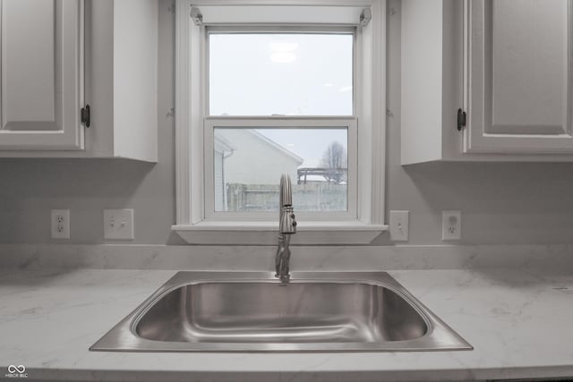 kitchen with sink, light stone countertops, and white cabinets