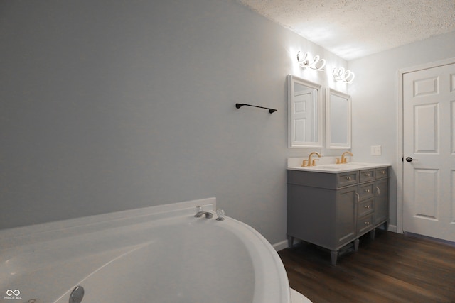 bathroom with hardwood / wood-style flooring, vanity, a bath, and a textured ceiling