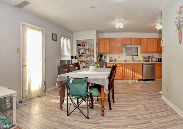 dining area with a textured ceiling, built in features, light hardwood / wood-style flooring, and sink