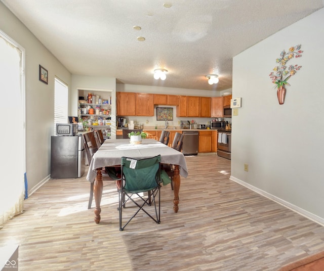 dining space featuring light wood-type flooring, a textured ceiling, and sink