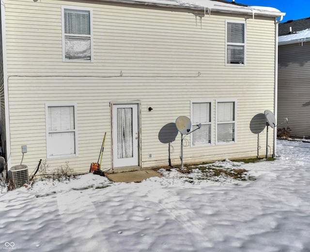 snow covered house featuring central air condition unit