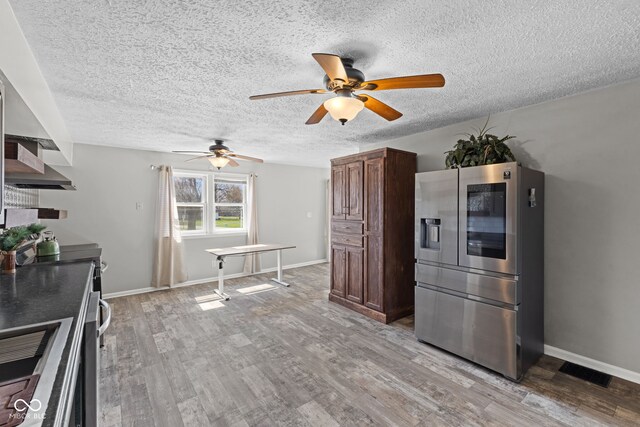 kitchen featuring light wood-type flooring, stainless steel appliances, baseboards, visible vents, and ceiling fan