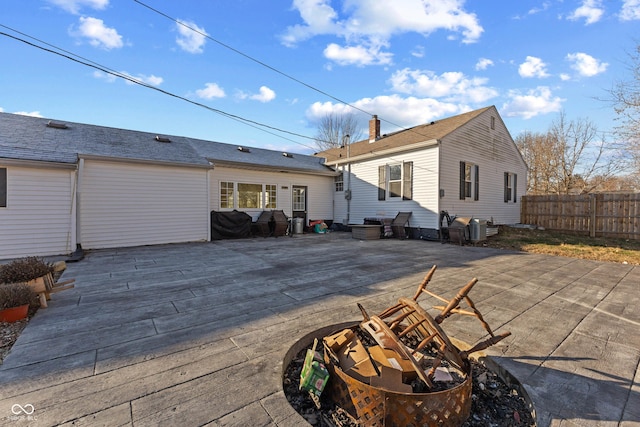 back of property featuring a chimney, fence, and a patio area