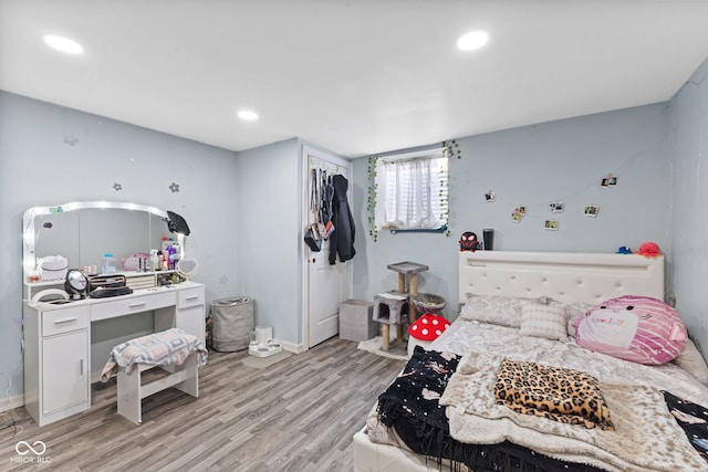 bedroom featuring a closet, baseboards, light wood-style flooring, and recessed lighting