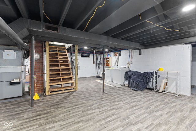 basement featuring heating unit, wood finished floors, stairway, and washer and clothes dryer