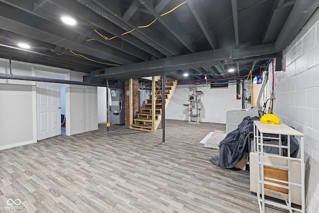 finished below grade area with heating unit, washer / dryer, stairway, and wood finished floors