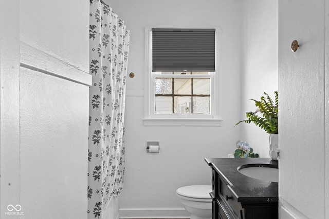 full bathroom featuring baseboards, a shower with shower curtain, toilet, and vanity