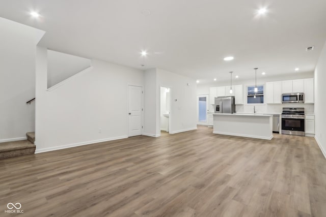 unfurnished living room with sink and light hardwood / wood-style flooring