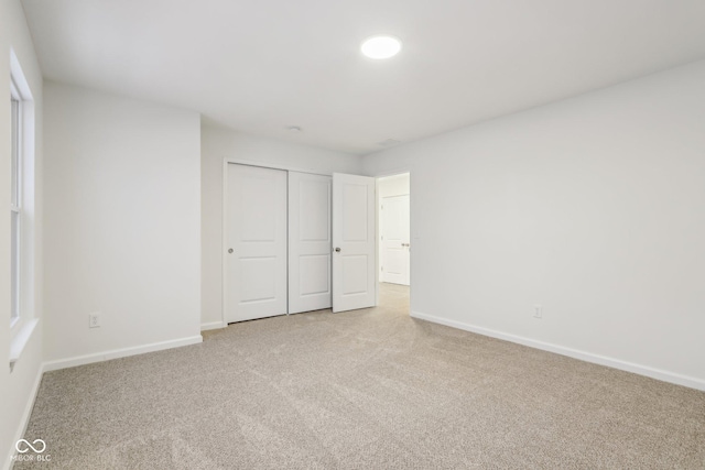 unfurnished bedroom featuring light carpet and a closet