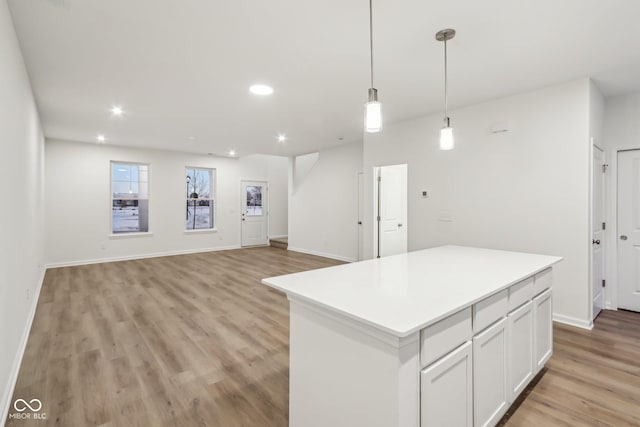 kitchen featuring light wood-type flooring, pendant lighting, white cabinetry, and a center island